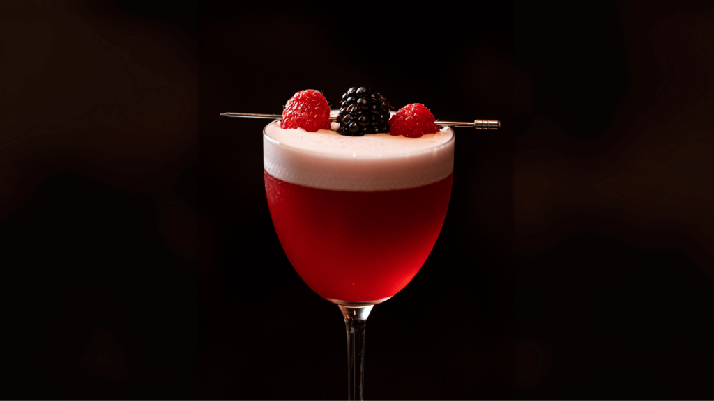A Rouge berry cocktail served in a glass with 3 berries as a garnish