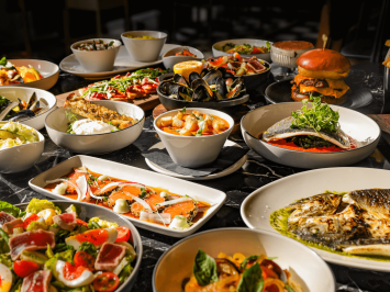 A table set out with a variety of plates of food from Bread Street Kitchens' spring menu. Seafood, salads, burgers, soups and sharing plates.