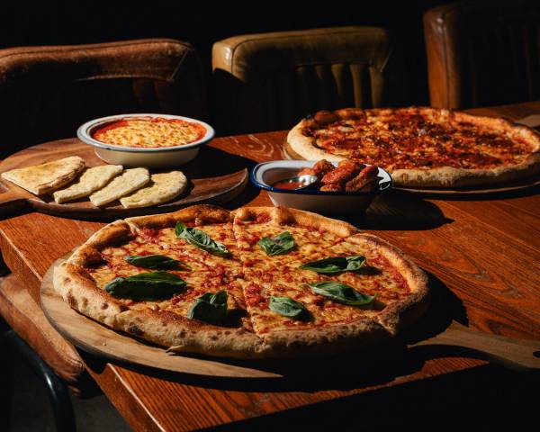 Selection of artisan pizzas served on wooden boards in rustic restaurant setting