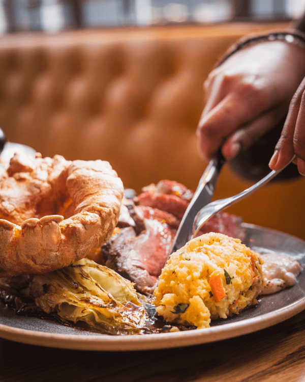 A person eating a plate of roast beef and trimmings at Bread Street Kitchen & Bar Limehouse