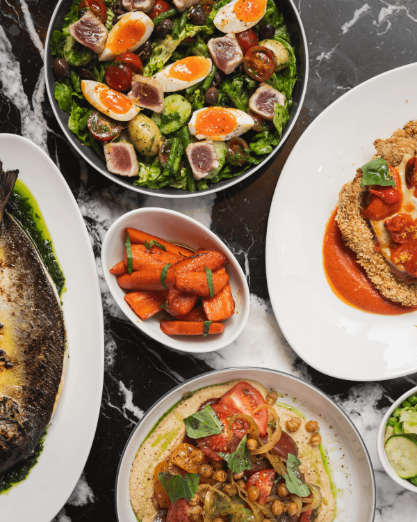 Plates of gourmet vegetables, carrots, salads, hummus and seafood