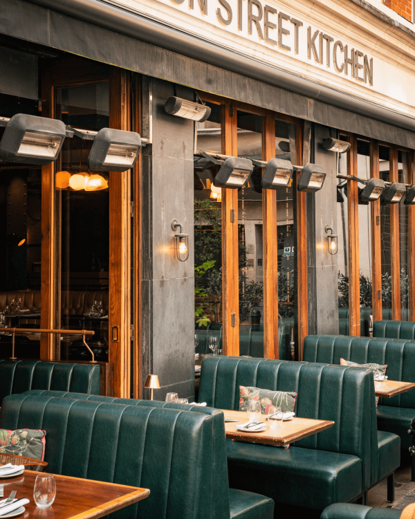 Booth tables set with glasses & cutlery in the outdoor dining area of the Heddon Street Kitchen Restaurant in Soho.