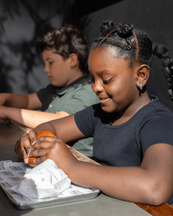 A young child enjoying a burger and fries from the Gordon Ramsay Kids Menu